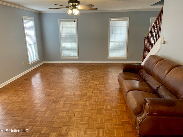 living room featuring ceiling fan, ornamental molding, a textured ceiling, and light parquet flooring