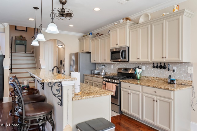 kitchen featuring hanging light fixtures, dark hardwood / wood-style flooring, a kitchen breakfast bar, a kitchen island with sink, and stainless steel appliances