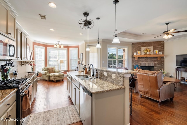 kitchen featuring appliances with stainless steel finishes, sink, decorative light fixtures, dark hardwood / wood-style floors, and a kitchen island with sink