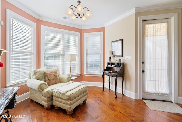 sitting room with a wealth of natural light, ornamental molding, hardwood / wood-style floors, and an inviting chandelier