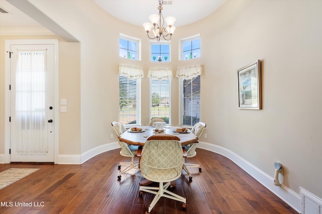 dining room featuring a towering ceiling, dark hardwood / wood-style floors, and a chandelier