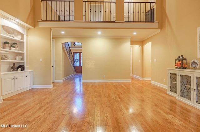 4655 Bonne Terre Dr, Nesbit, MS 38651 - unfurnished living room featuring a towering ceiling, arched walkways, stairs, wood finished floors, and baseboards