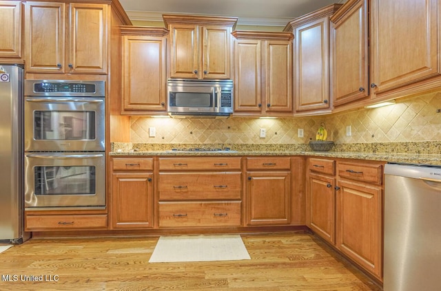 4655 Bonne Terre Dr, Nesbit, MS 38651 - kitchen with stainless steel appliances, light wood finished floors, light stone counters, and backsplash