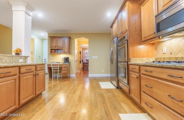 4655 Bonne Terre Dr, Nesbit, MS 38651 - kitchen with stainless steel appliances, arched walkways, decorative columns, backsplash, and light wood-style floors