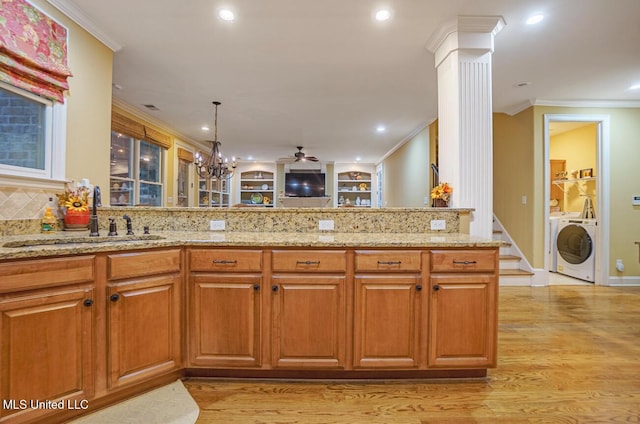 4655 Bonne Terre Dr, Nesbit, MS 38651 - kitchen with a sink, decorative columns, light stone countertops, light wood-type flooring, and crown molding