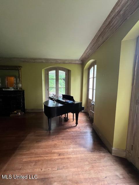 sitting room with wood finished floors, baseboards, ornamental molding, and arched walkways