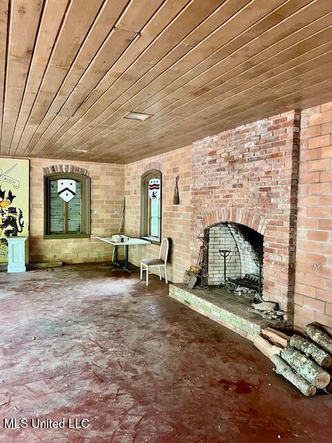 unfurnished living room with wooden ceiling, arched walkways, brick wall, a brick fireplace, and concrete flooring
