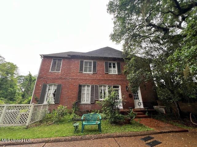 view of front of home featuring fence and brick siding