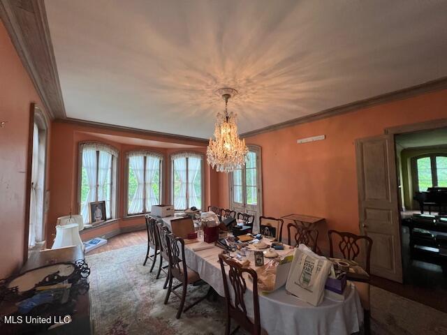 dining space with ornamental molding, a notable chandelier, and wood finished floors
