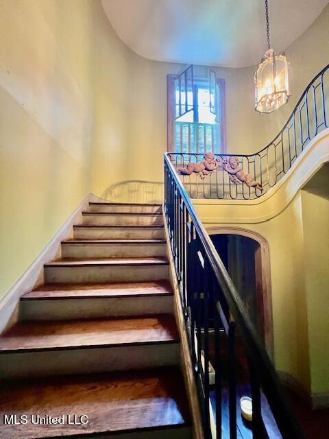 stairway with baseboards, a notable chandelier, and a towering ceiling