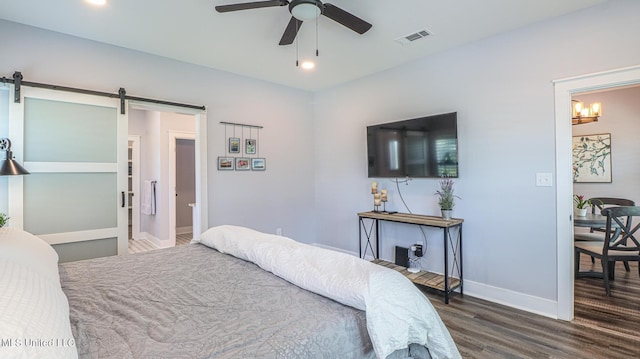 bedroom with dark wood-type flooring, ceiling fan, and a barn door