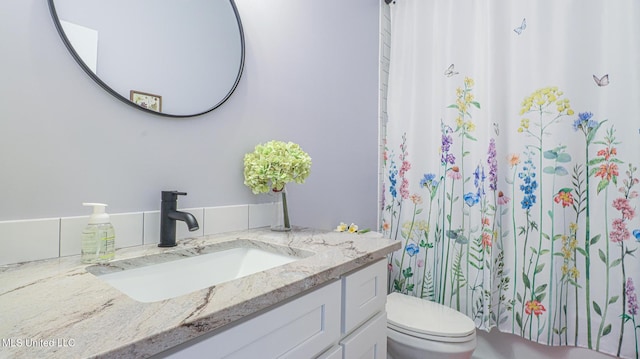 bathroom featuring toilet, vanity, and a shower with shower curtain