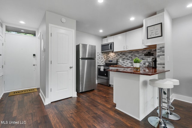 123A Lakeside Villa Dr Unit C, Diamondhead, MS 39525 - kitchen featuring dark wood-style flooring, stainless steel appliances, a breakfast bar, a sink, and a peninsula