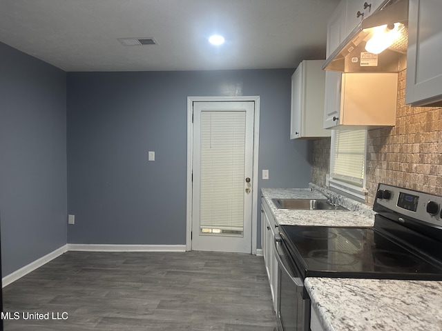 kitchen featuring dark wood-style flooring, visible vents, stainless steel electric range oven, a sink, and under cabinet range hood