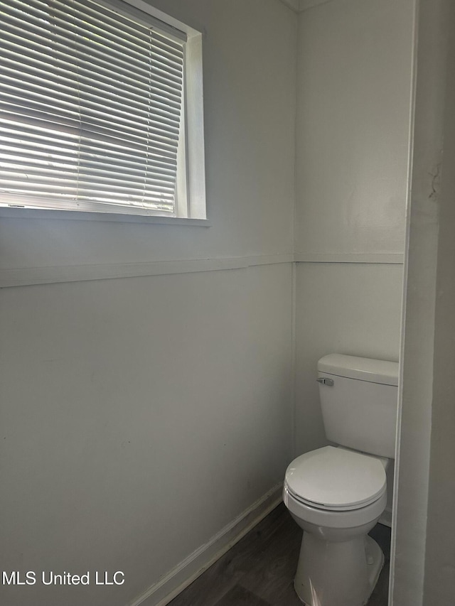 bathroom with toilet, baseboards, and wood finished floors