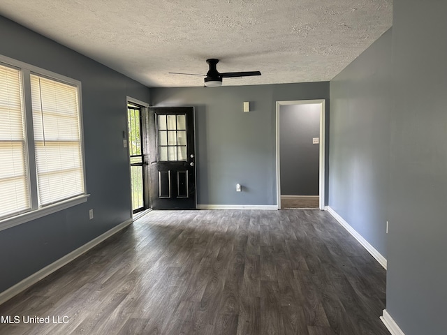 empty room with baseboards, a textured ceiling, dark wood-style floors, and ceiling fan