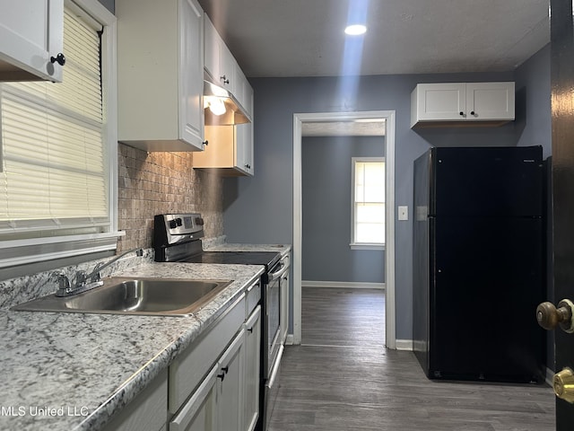 kitchen featuring stainless steel electric range oven, tasteful backsplash, a sink, baseboards, and freestanding refrigerator