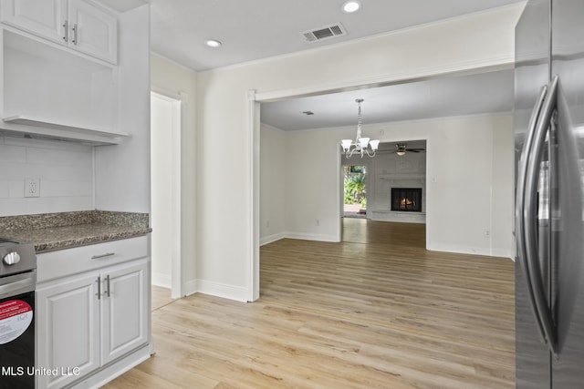 122 Carroll Ave, Long Beach, MS 39560 - kitchen with freestanding refrigerator, light wood-style flooring, white cabinets, crown molding, and a lit fireplace