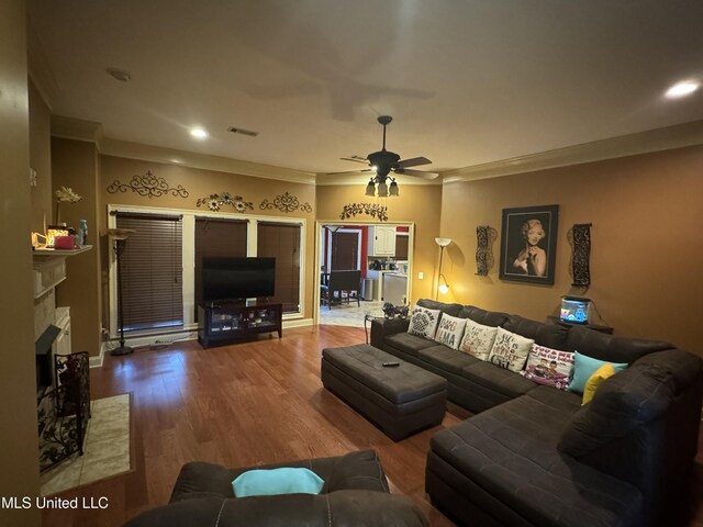 living room featuring a fireplace, ceiling fan, crown molding, and wood-type flooring