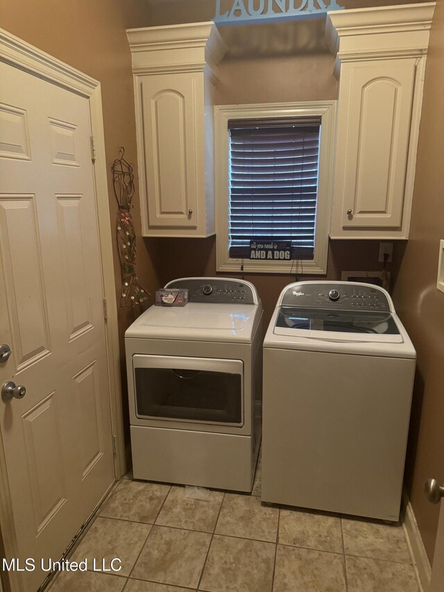 washroom featuring cabinets, light tile patterned floors, and washing machine and clothes dryer