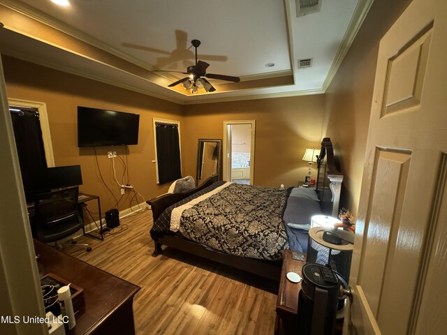 bedroom with ceiling fan, light hardwood / wood-style floors, a raised ceiling, and crown molding
