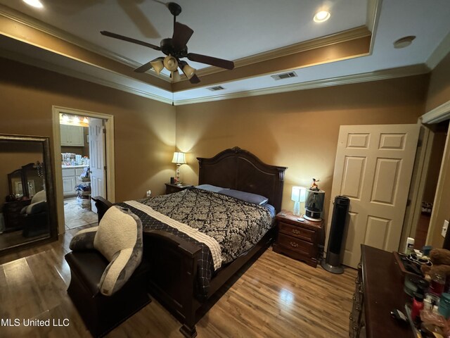 bedroom with wood-type flooring, a tray ceiling, ceiling fan, and ornamental molding