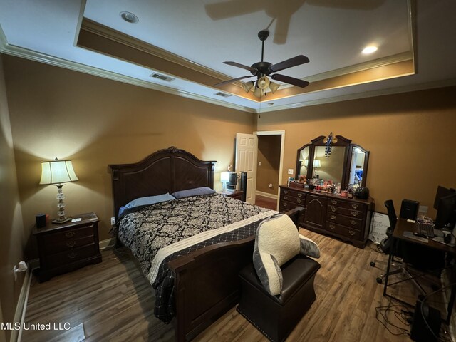 bedroom featuring hardwood / wood-style floors, a tray ceiling, ceiling fan, and ornamental molding