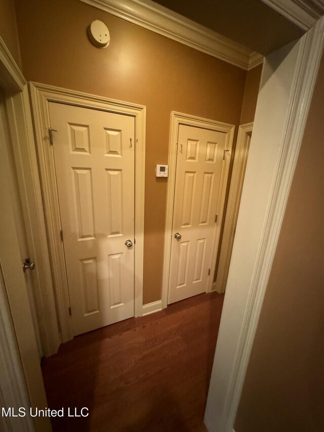 corridor with dark hardwood / wood-style flooring and ornamental molding