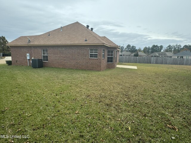 back of property featuring a lawn and central air condition unit