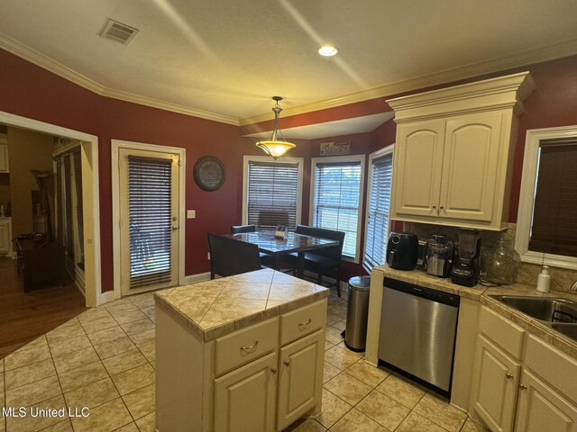 kitchen with dishwasher, hanging light fixtures, ornamental molding, light tile patterned floors, and tile counters