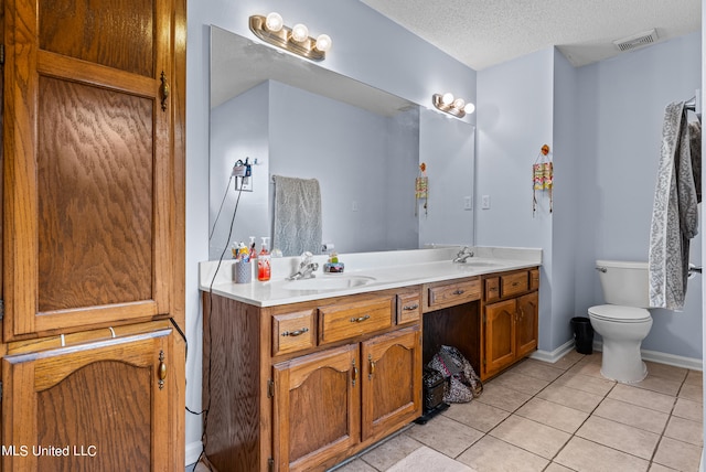 bathroom featuring toilet, a textured ceiling, vanity, and tile patterned floors