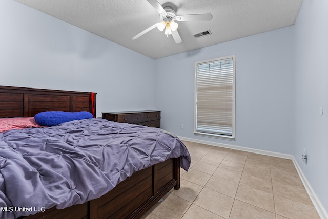 bedroom with a textured ceiling, light tile patterned floors, and ceiling fan