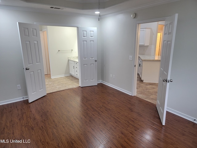 unfurnished bedroom with dark wood finished floors, visible vents, crown molding, and baseboards