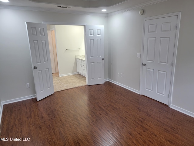 unfurnished room with crown molding, dark wood-style floors, visible vents, and baseboards