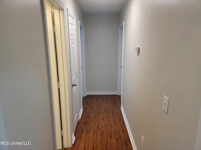 hallway with dark wood-type flooring and baseboards