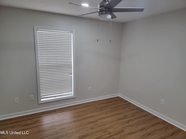 spare room with baseboards, ceiling fan, and wood finished floors