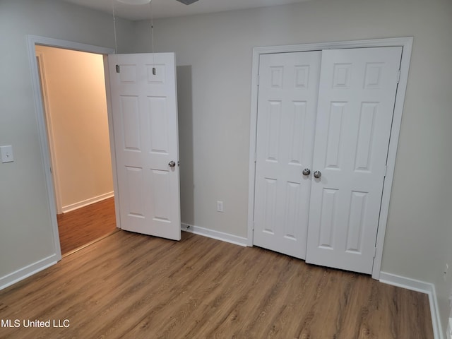 unfurnished bedroom featuring a closet, baseboards, and wood finished floors