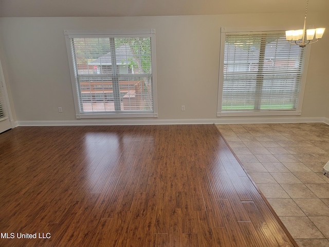 empty room featuring baseboards, wood finished floors, and a chandelier