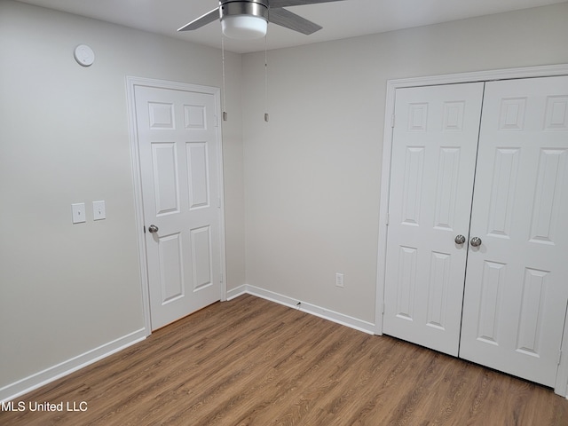 unfurnished bedroom with a closet, ceiling fan, baseboards, and wood finished floors