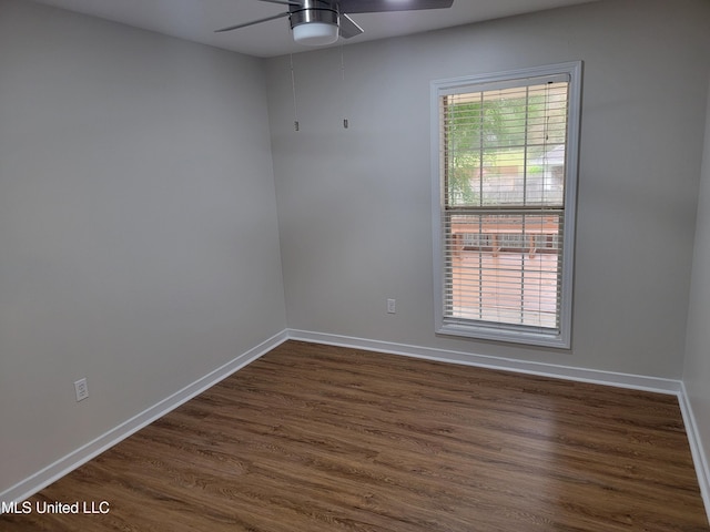 empty room featuring attic access, a ceiling fan, dark wood-style flooring, and baseboards