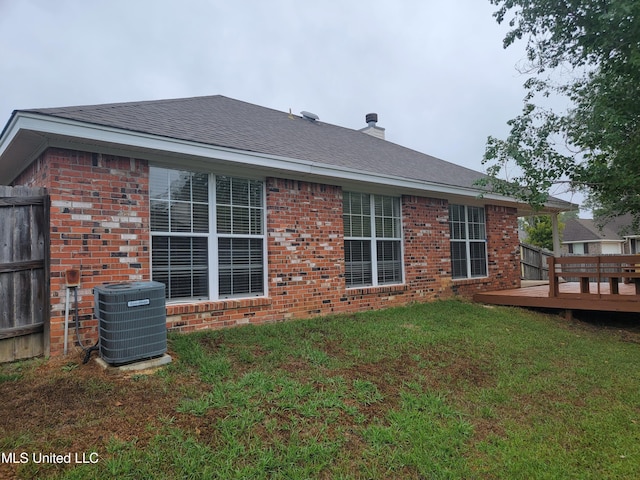 back of house featuring brick siding, a yard, a shingled roof, and central AC