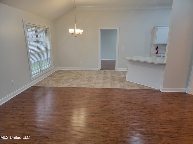 unfurnished dining area featuring baseboards, light wood-type flooring, ornamental molding, vaulted ceiling, and an inviting chandelier