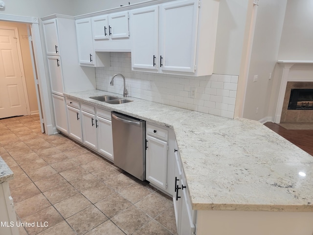 kitchen with dishwasher, white cabinetry, backsplash, and a sink