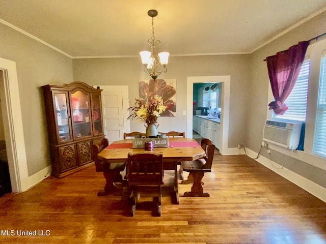 dining space with baseboards, ornamental molding, wood finished floors, and an inviting chandelier