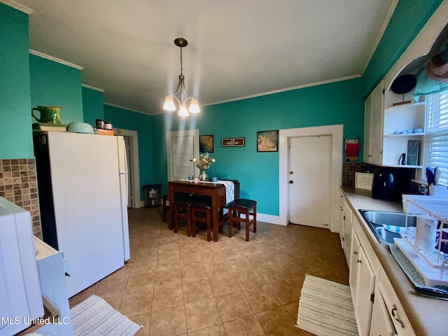 kitchen with light tile patterned floors, white cabinetry, crown molding, and freestanding refrigerator