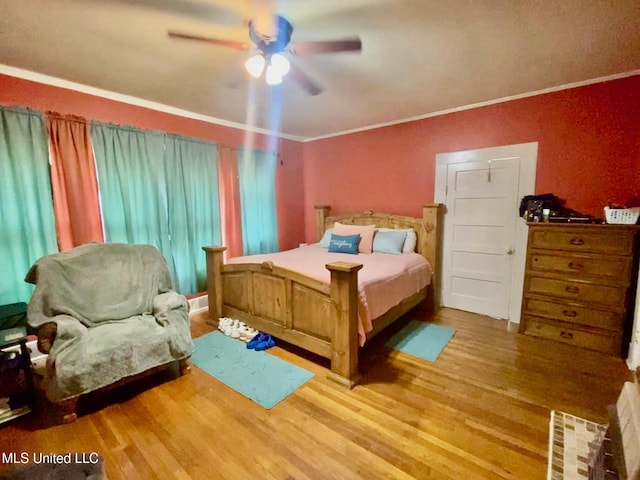bedroom featuring a ceiling fan, crown molding, and wood finished floors