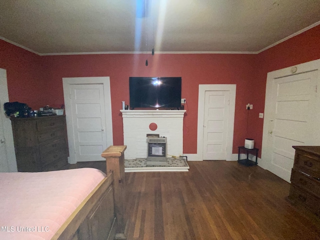 bedroom with ornamental molding, wood finished floors, and a brick fireplace
