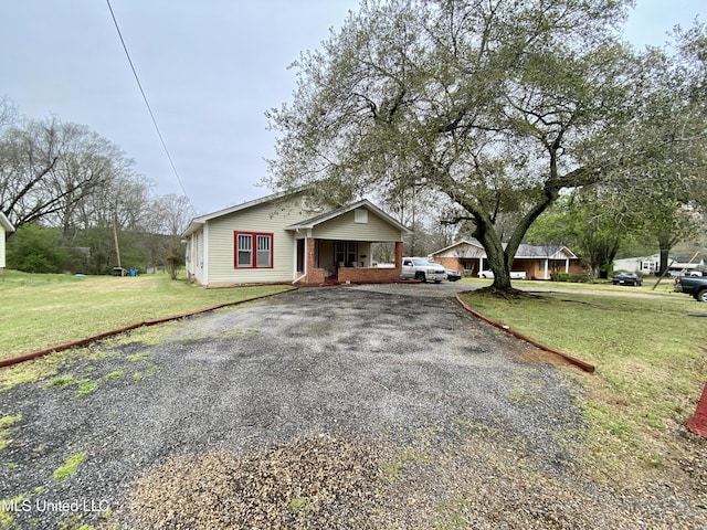 view of front of home featuring covered porch, a front lawn, and gravel driveway