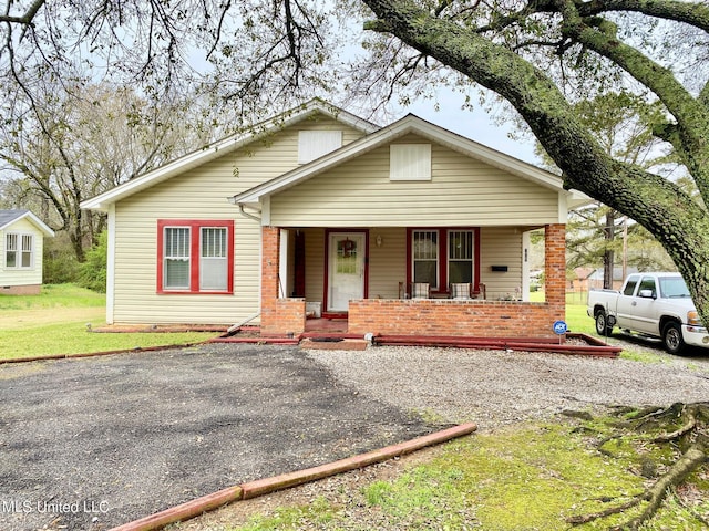 bungalow-style house with covered porch, brick siding, and driveway