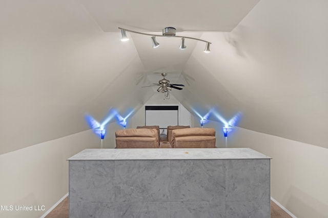 cinema room with ceiling fan, track lighting, and vaulted ceiling